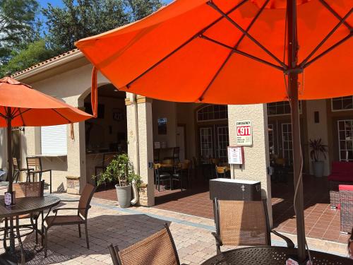 a patio with tables and chairs with an orange umbrella at Awesome Mediterranean Resort! 15 minutes to Disney in Kissimmee