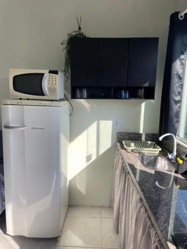 a kitchen with a white refrigerator and a microwave at Mini casa perto BC, Penha in Itajaí