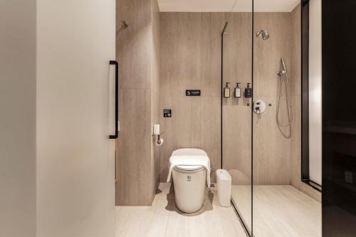 a bathroom with a toilet and a glass shower at Xiyada Hotel（Chongqing Guanyinqiao） in Chongqing