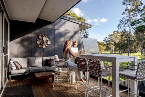 two people standing at a bar on the deck of a house at Pandanas 17B at Mollymook Beach in Mollymook