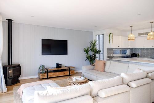 a living room with a white couch and a kitchen at Pandanas 17B at Mollymook Beach in Mollymook