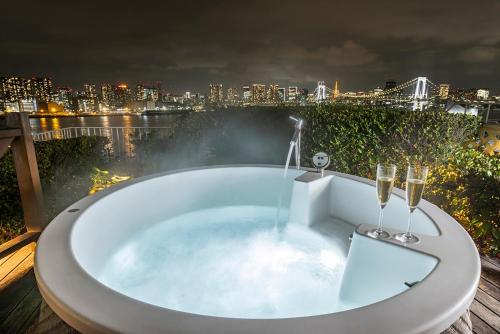 a bath tub with two champagne glasses and a city skyline at Hilton Tokyo Odaiba in Tokyo