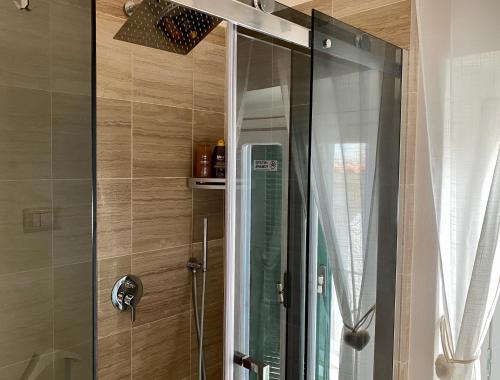 una ducha con puerta de cristal en un baño en Cozy Sea View Flat with Private 83 sq Rooftop, Balcony, and BBQ in the Old Town, en Vieste