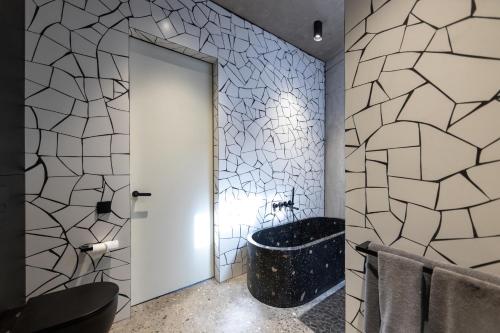 La salle de bains est pourvue d'une baignoire et d'un mur en carrelage. dans l'établissement Predmet Kabakaba Village Tabanan Bali, à Tumbak Bayuh