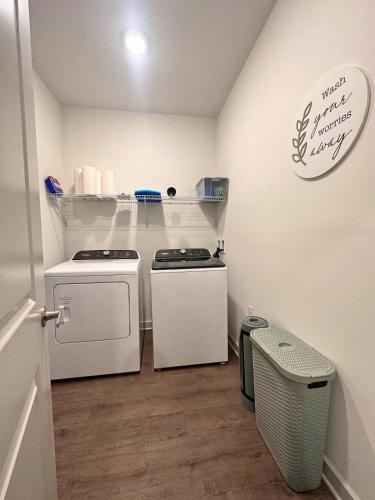a small laundry room with two washes and a trash can at Modern Oasis with King Bed, Fireworks View, 10 Minutes to Disney in Orlando