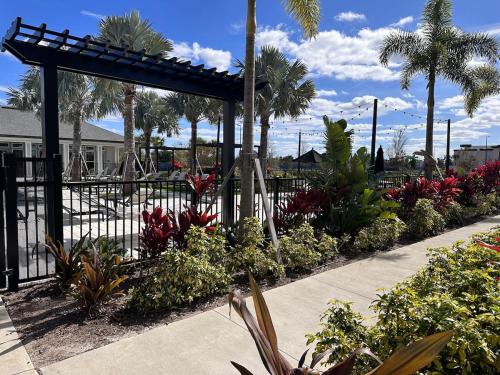 a garden with flowers and a fence and palm trees at Modern Oasis with King Bed, Fireworks View, 10 Minutes to Disney in Orlando