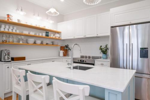 a kitchen with white cabinets and a large white island at Sea Sage Cottage 4703 in Yeppoon