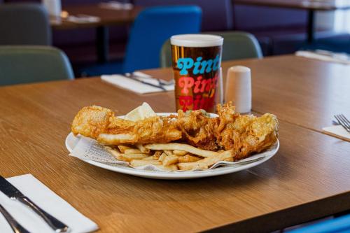 a plate of fried chicken and french fries with a drink at Holiday Inn Express Aberdeen Airport by IHG in Dyce
