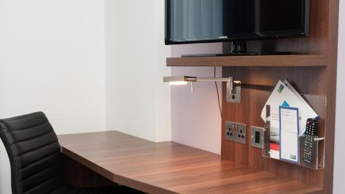 a desk with a tv and a chair in a room at Holiday Inn Express Aberdeen Airport by IHG in Dyce