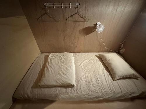 a bed with white sheets and pillows in a room at 石垣ゲストハウスオハナ in Ishigaki Island
