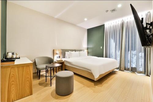 a bedroom with a bed and a desk with a chair at The Hound Hotel Changwon Terminal in Changwon