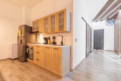 a kitchen with wooden cabinets and a refrigerator at 6 bedroom with Jacuzzi 1 block from LLeras P10 in Medellín