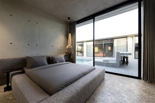 une chambre avec un grand lit et une grande fenêtre dans l'établissement Predmet Kabakaba Village Tabanan Bali, à Tumbak Bayuh