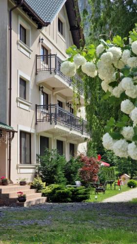 a building with balconies and flowers in front of it at PENSIUNEA DIMITRIOS Relaxare cu jacuzzi pe Valea Cernei in Băile Herculane