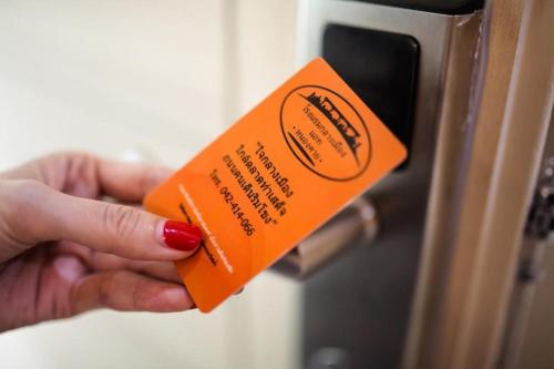 a person holding an orange card in front of a door at Klang Muang @ Nongkhai Hotel in Nong Khai