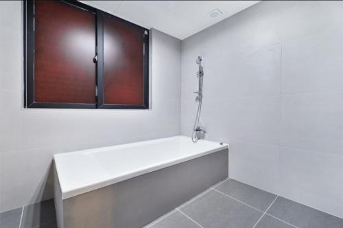 a white bathroom with a bath tub and a window at The Hound Hotel Changwon Terminal in Changwon