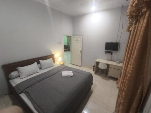 a bedroom with a bed and a desk and a television at Asoka Homestay Yogyakarta in Demangan
