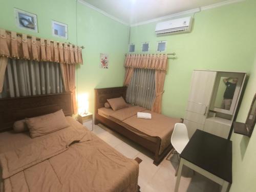 a small bedroom with two beds and a desk at Asoka Homestay Yogyakarta in Demangan