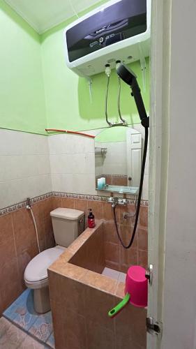 a bathroom with a toilet and a tv on the wall at Asoka Homestay Yogyakarta in Demangan