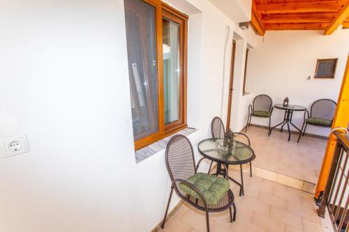 a balcony with tables and chairs and a window at Psarotherma Rooms in Samothraki