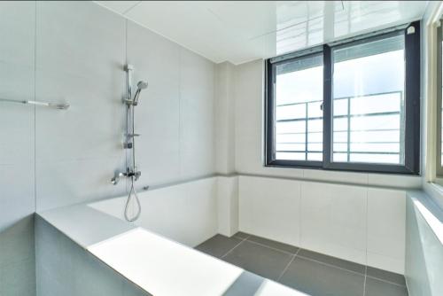 a white bathroom with a shower and a tub at The Hound Hotel Changwon Terminal in Changwon