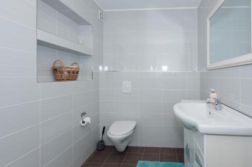 a white bathroom with a toilet and a sink at Vestre apartment in Ålesund