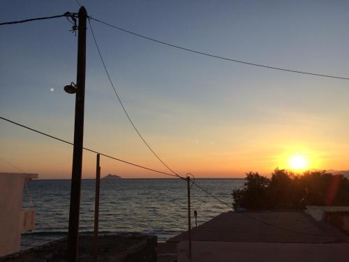 una puesta de sol sobre el océano con un poste de teléfono en Crysalis Studios, en Kalamaki
