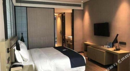 a bedroom with a bed and a desk and a television at Echarm Hotel Changde Taoyuan Walking Street Jinyuan Tower in Changde