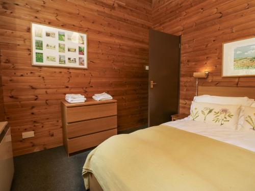a bedroom with a bed and a wooden wall at Grasmere in Ulverston