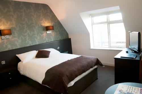 um quarto de hotel com uma cama e uma televisão em Dinn Rí Hotel em Carlow