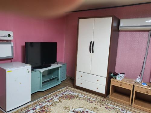 a living room with a tv and a room with pink walls at 오색약수온천모텔 Osaek Hot Spring Motel in Yangyang