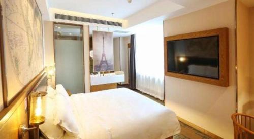 a hotel room with a bed and a flat screen tv at James Joyce Coffetel Changchun People's Square in Changchun