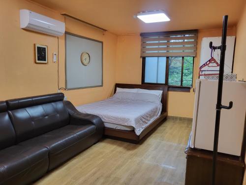 a bedroom with a bed and a leather couch at 오색약수온천모텔 Osaek Hot Spring Motel in Yangyang