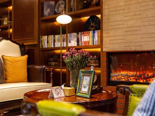 a living room with a fireplace and a table with flowers at James Joyce Coffetel Kunming Railway Station Huancheng Nan Road Metro Station in Kunming