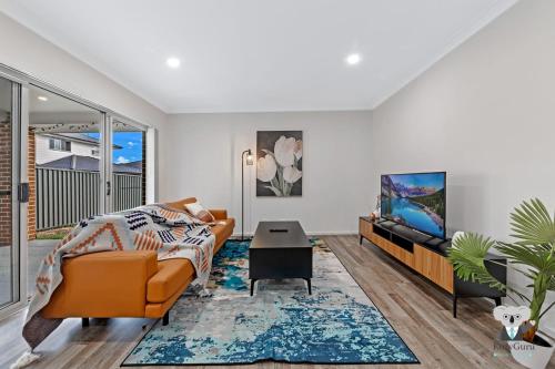 a living room with a couch and a tv at KozyGuru | Austral | 5 Bed Comfy House in Horningsea Park