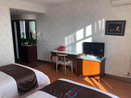 a hotel room with a desk and a television at Pai Hotel Ordos Dongsheng District Yingbin Road in Ordos