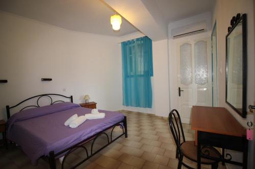 a bedroom with a bed with purple sheets and a table at Belvedere Paleo in Paleokastritsa