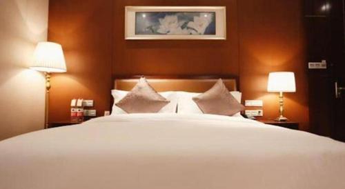 a bedroom with a large white bed with two lamps at Balan International Hotel in Dujiangyan