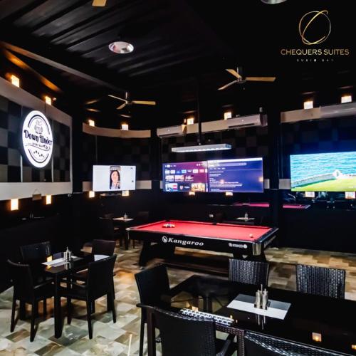 a restaurant with a pool table and televisions at Chequers Suites Subic Bay in Olongapo