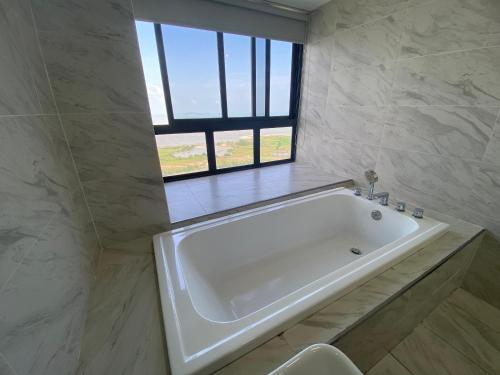 a white bath tub in a bathroom with a window at Imperio Residence Melaka by Jeffery Lam Home Management in Melaka