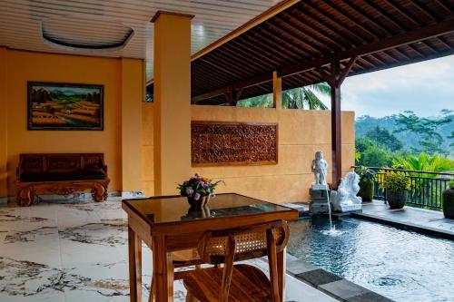 a living room with a table and a pool at Grand Campuhan in Tegalalang
