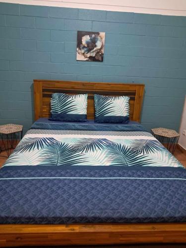 a bedroom with a wooden bed with blue walls at La kaz de l'arbre voyageur in LʼEntre-Deux