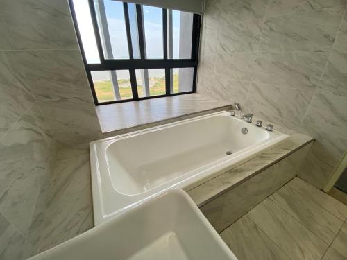 a white bath tub in a bathroom with a window at Imperio Residence Melaka by Jeffery Lam Home Management in Melaka
