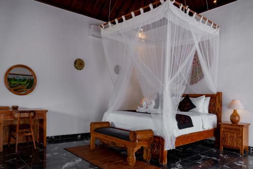 a bedroom with a canopy bed and a chair at Grand Campuhan in Tegalalang