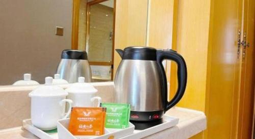 a coffee pot on a counter in front of a mirror at Vienna Hotel Guangxi Fangcheng in Fangcheng