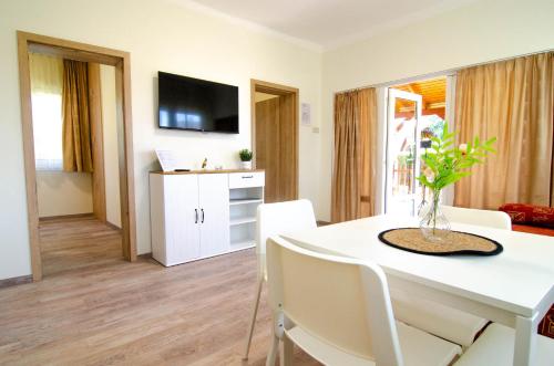 a living room with a white table with chairs and a tv at Heu Réka Vendégház in Dunasziget