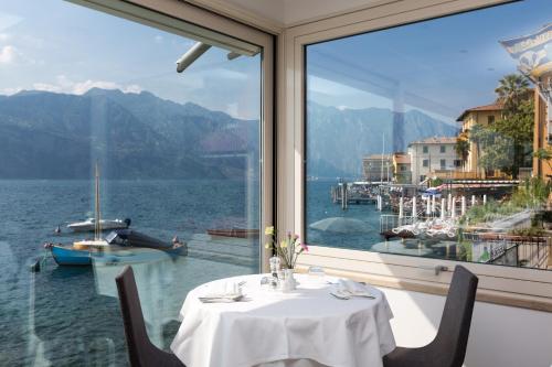 a table in a restaurant with a view of the water at Hotel Vega in Malcesine