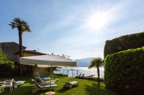 a patio with an umbrella and chairs and a view of the water at Hotel Vega in Malcesine