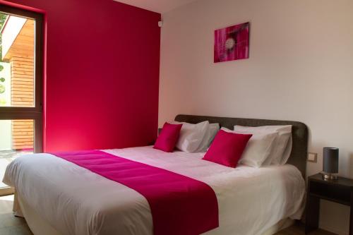 a bedroom with a large bed with a red wall at Le Gallus in Boersch