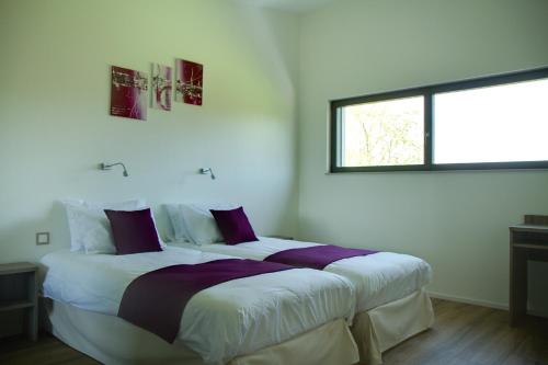 a white bedroom with a large bed with purple pillows at Le Gallus in Boersch